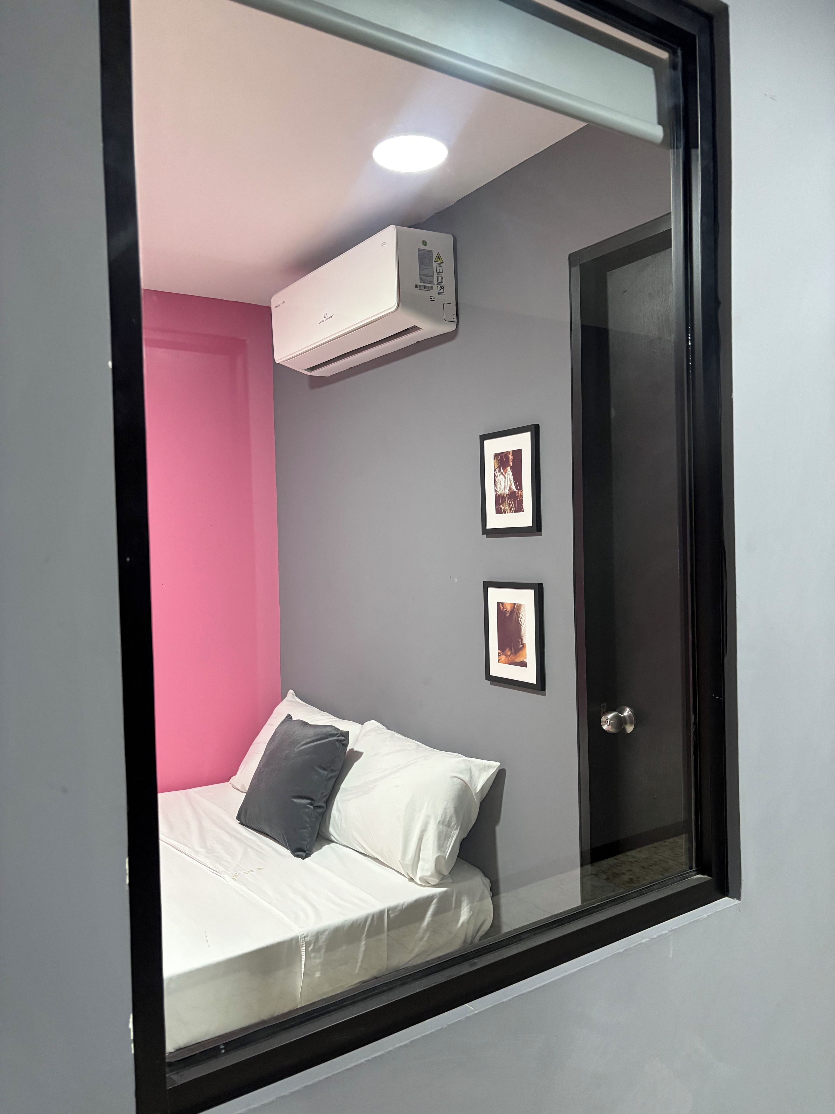 Una habitación con una cama, una puerta y un equipo de aire acondicionado en la pared.