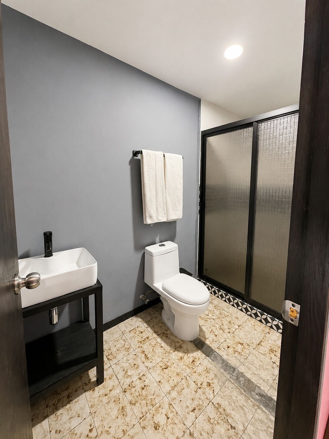 Een badkamer met een witte wastafel, toilet en een handdoek aan de muur.