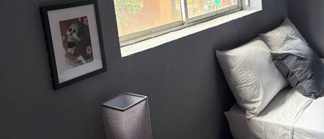 Una habitación con cama, una mesita de noche con lámpara, un control remoto y dos cuadros en la pared.