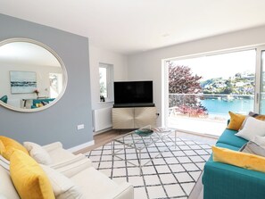 A modern living room with a large window, a flat-screen TV, a sofa, and a coffee table. - Galvayne (Dartmouth)