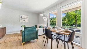 A modern dining area with a wooden table set for four, a green sofa, and a white couch. - Cozy Creekside Landing (Branson)