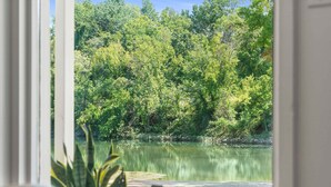 A view from inside a room looking out to a lake surrounded by dense trees. - Cozy Creekside Landing (Branson)