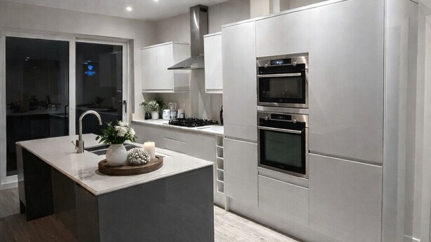 Ett modernt kök med en central köksö, apparater i rostfritt stål och en stilren design.
