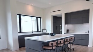Een moderne keuken met een groot eiland, barstoelen en inbouwapparatuur.