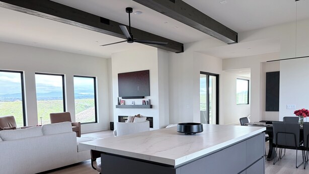 Een moderne keuken met een groot eiland, inbouwapparatuur en een eethoek met uitzicht op de omgeving.