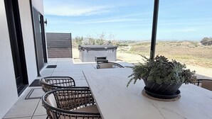 Een terras met een tafel en stoelen, een bloempot en uitzicht op het landschap.