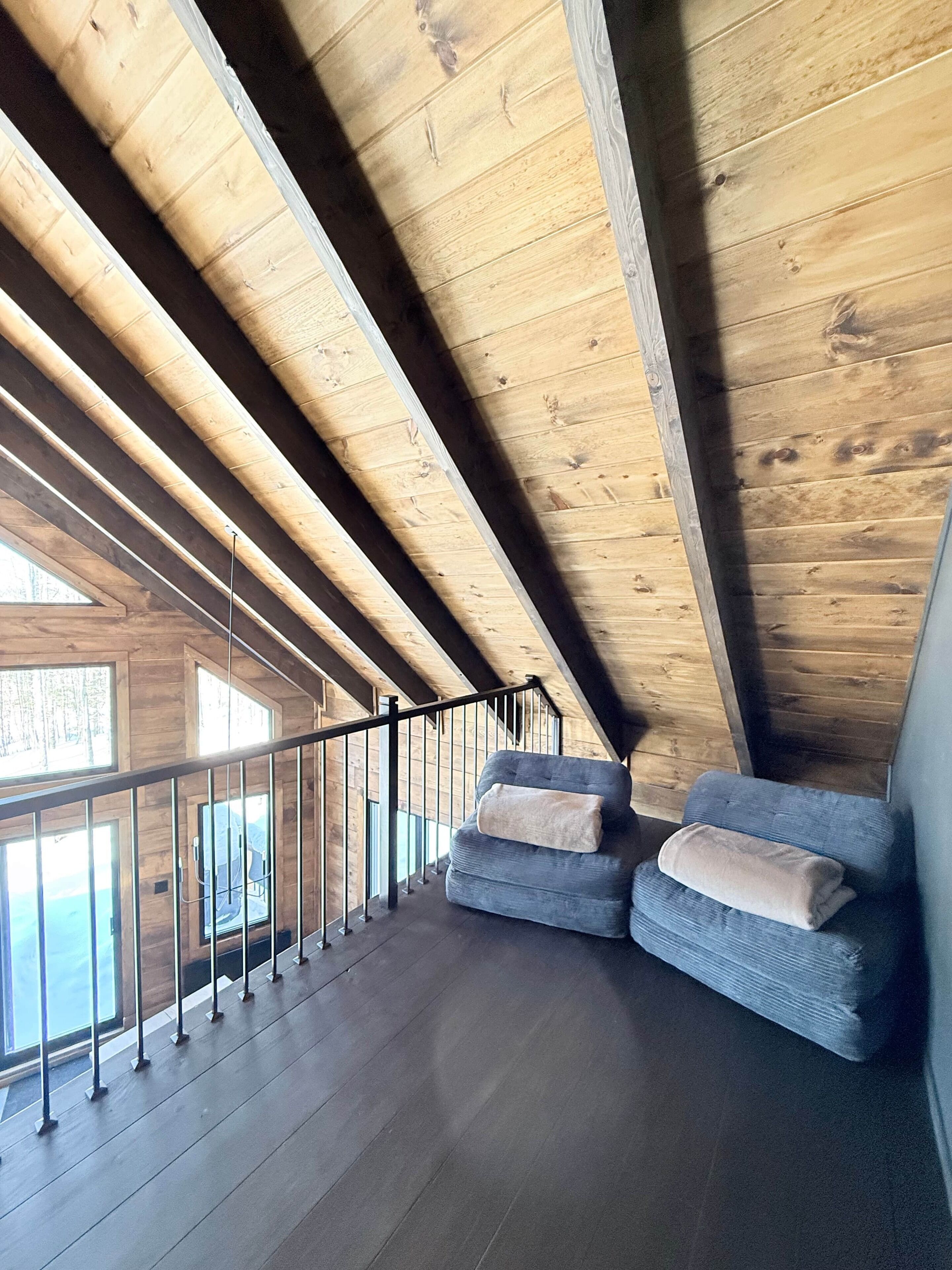 Een houten interieur met een balkon, een bank en een leuning.