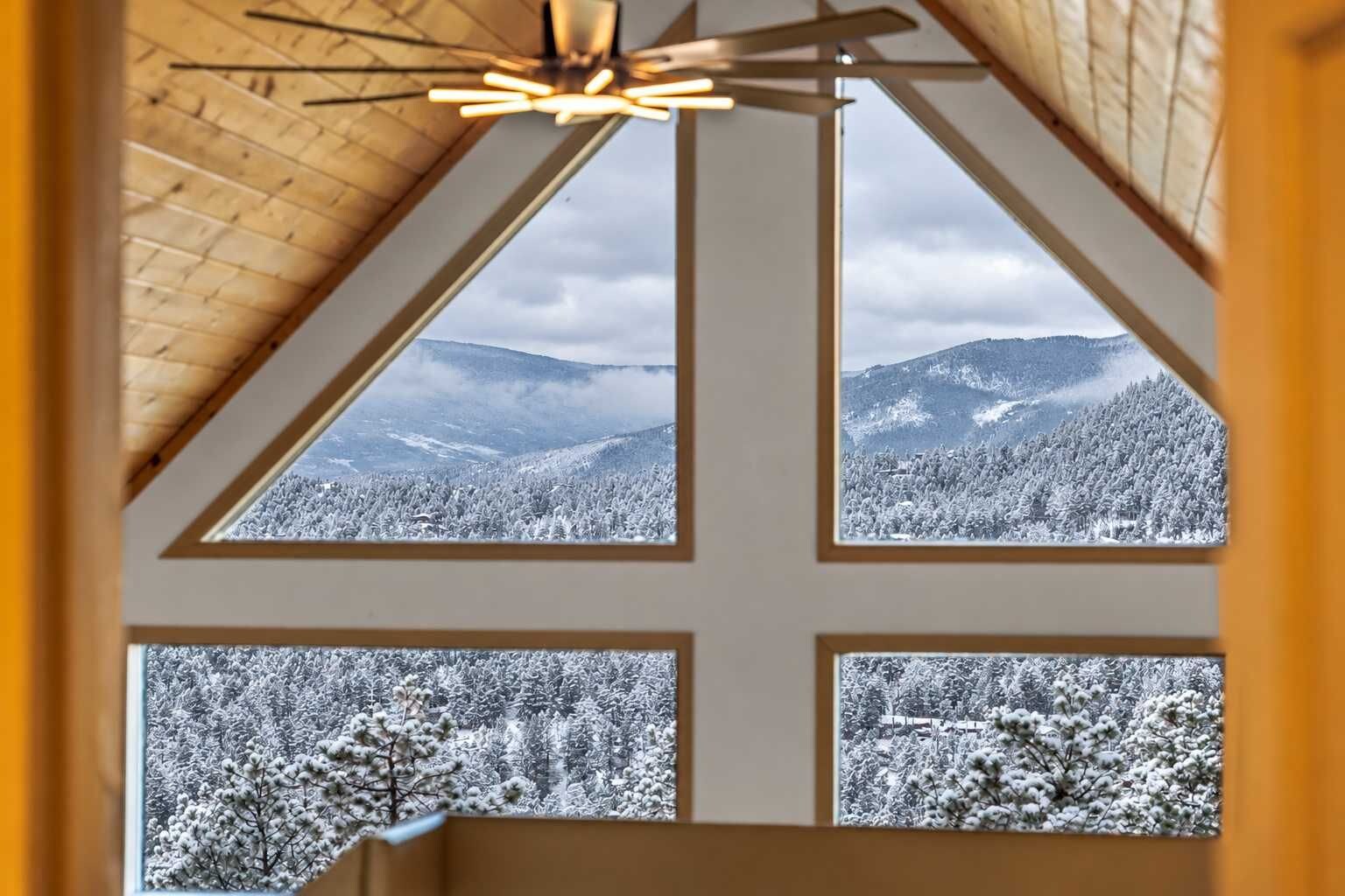 A room with a sloped ceiling and four windows offering a view of a snowy landscape.