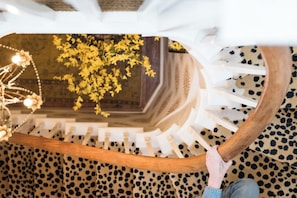 A staircase with a wooden handrail and a leopard print carpet. - Kubli Haus (Jacksonville)