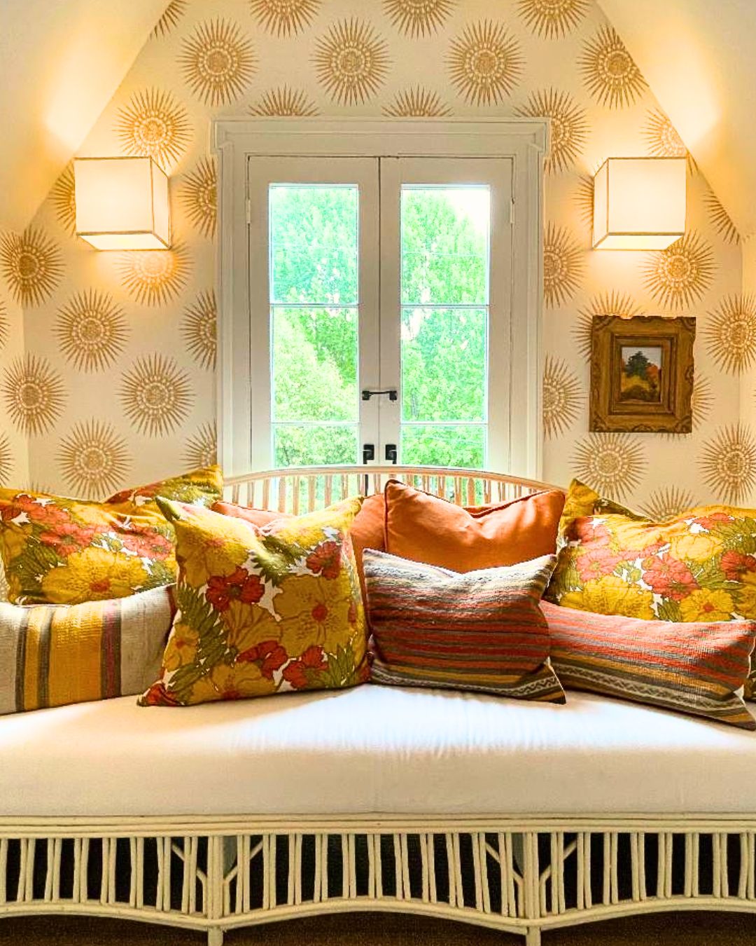 A cozy room with a white bench, floral cushions, and a window with a view of greenery.