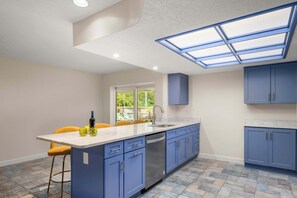 Una cocina moderna con armarios azules, una isla central y un tragaluz.