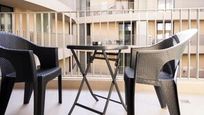 Ein moderner Außenbereich zum Sitzen mit Tisch und Stühlen, umgeben von einem Balkon mit Geländer.