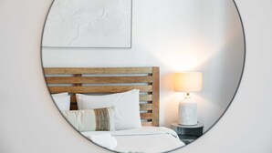 Een slaapkamer met een houten hoofdbord, een bedlampje en een lijst met een kunstwerk aan de muur.