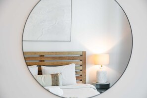 Ein Schlafzimmer mit hölzernem Kopfteil, einer Nachttischlampe und einem gerahmten Kunstwerk an der Wand.