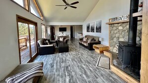 A spacious living room with a high ceiling, a fireplace, and a stone accent wall. - Ski Chalet - Views, Hot Tub, Game Room (Angel Fire)