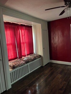 A room with a built-in bench with floral cushions, a ceiling fan, and a red wall. - Two bedroomhome to rent Thursday through Sunday morning for NFL draft (Pittsburgh)