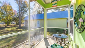 Eine Veranda mit Tisch und Stühlen, ein Schild mit der Aufschrift "The Porch Sit & Relax" und Blick auf ein Gebäude mit blauem Dach.
