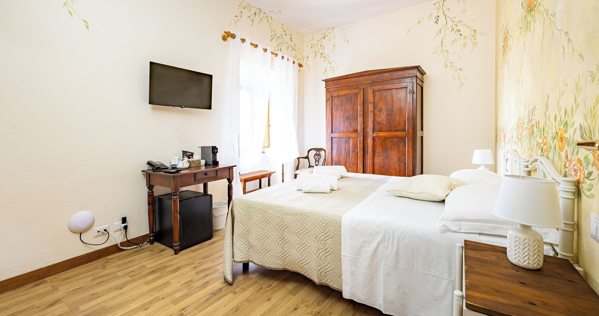 Une chambre à coucher comprenant un lit, un bureau, une armoire, une télévision et une salle de bain avec un miroir et un lavabo.
