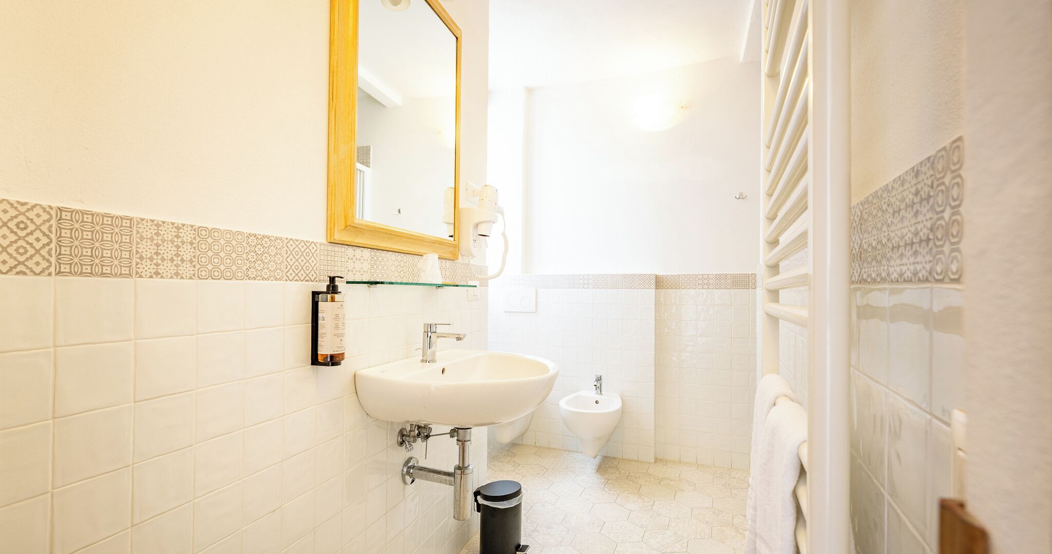 A bathroom with a sink, bidet, and mirror.