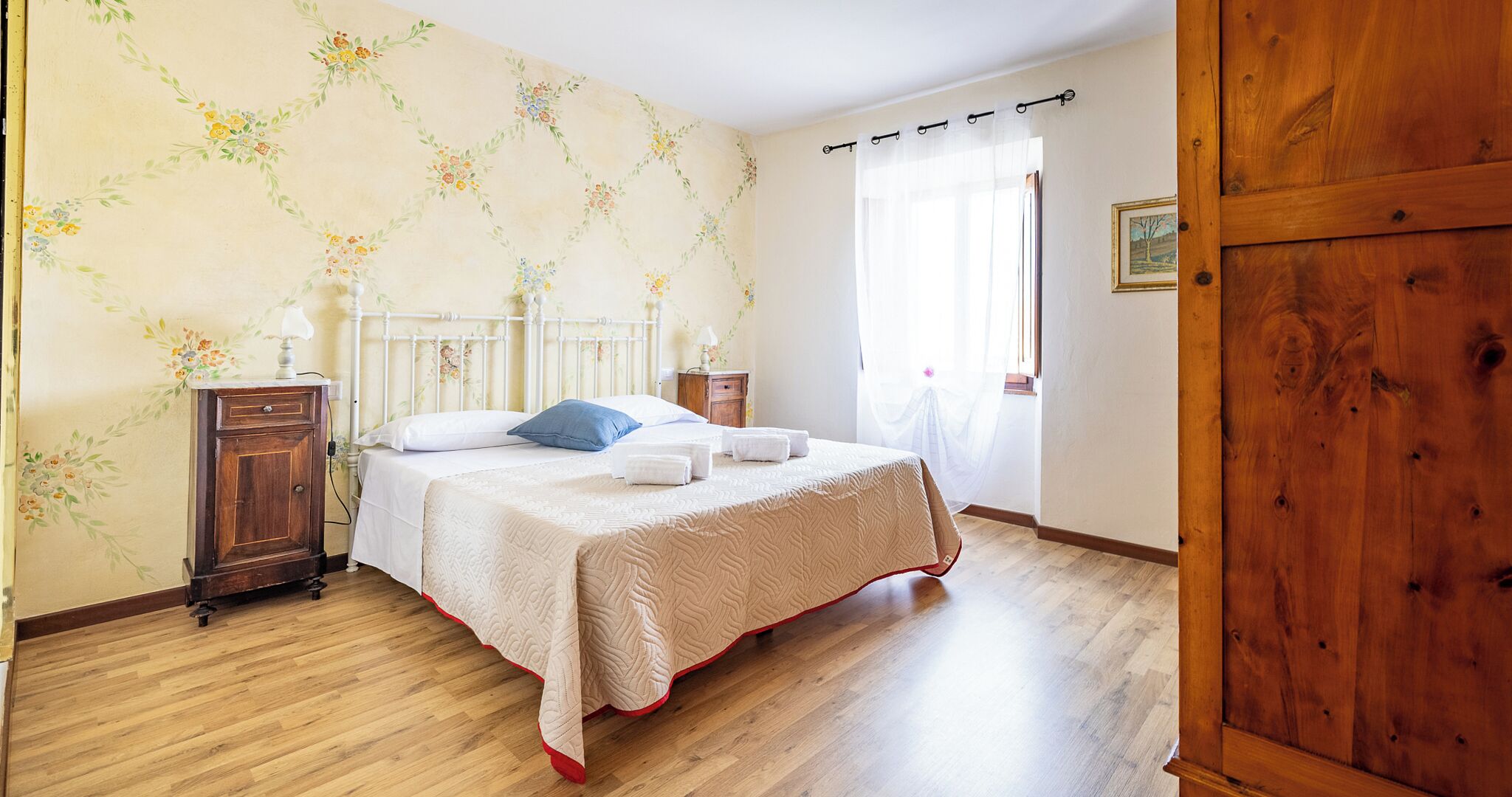 Een slaapkamer met een bed, een houten garderobe en een nachtkastje.