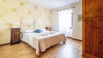 Een slaapkamer met een bed, een houten garderobe en een nachtkastje.