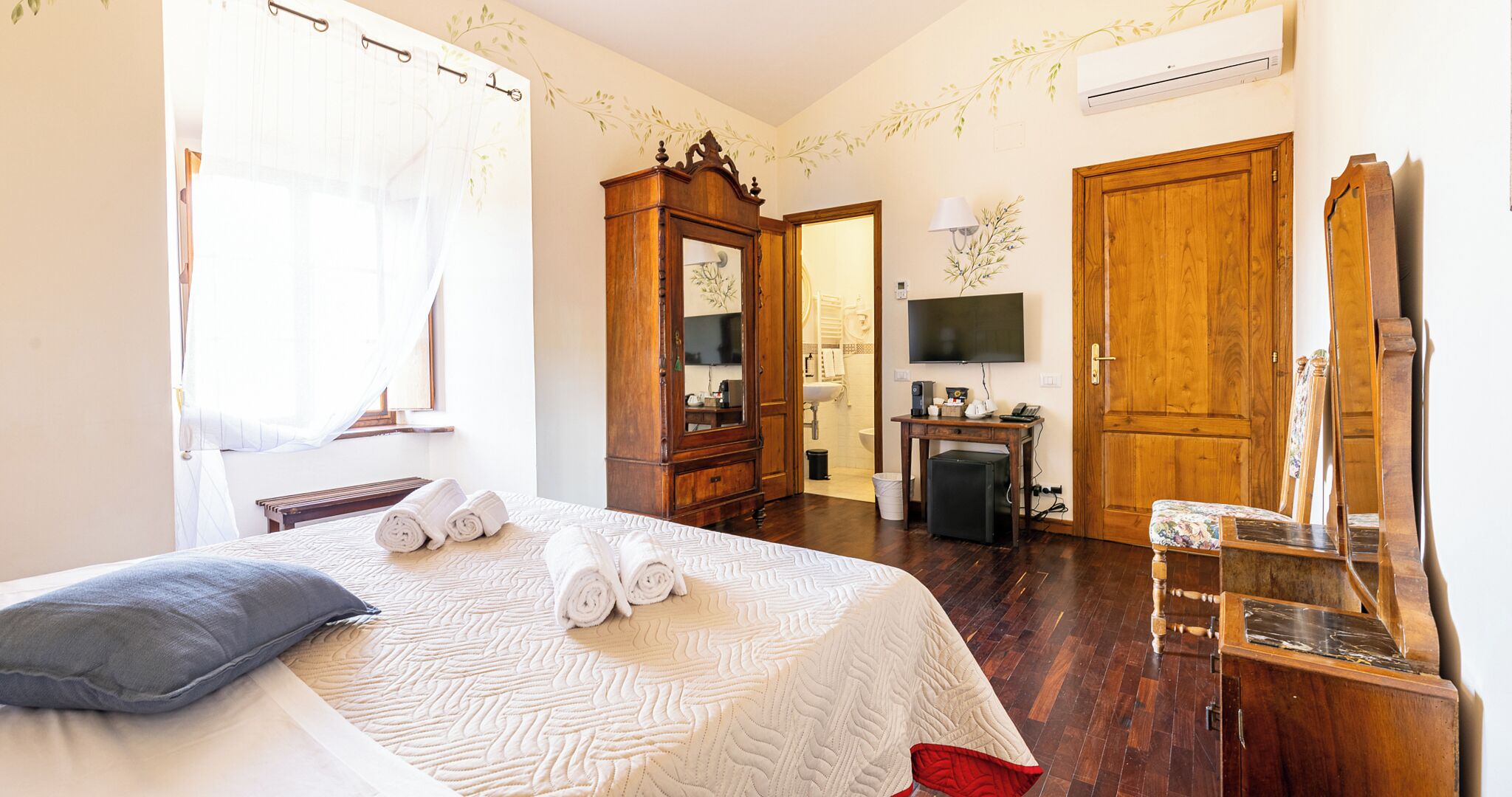 A hotel room with a bed, a desk, a television, and a wardrobe.
