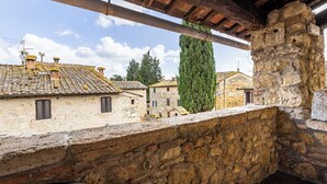A stone balcony overlooking traditional buildings with tiled roofs and a clear sky. - Locanda Casalta (Strove)