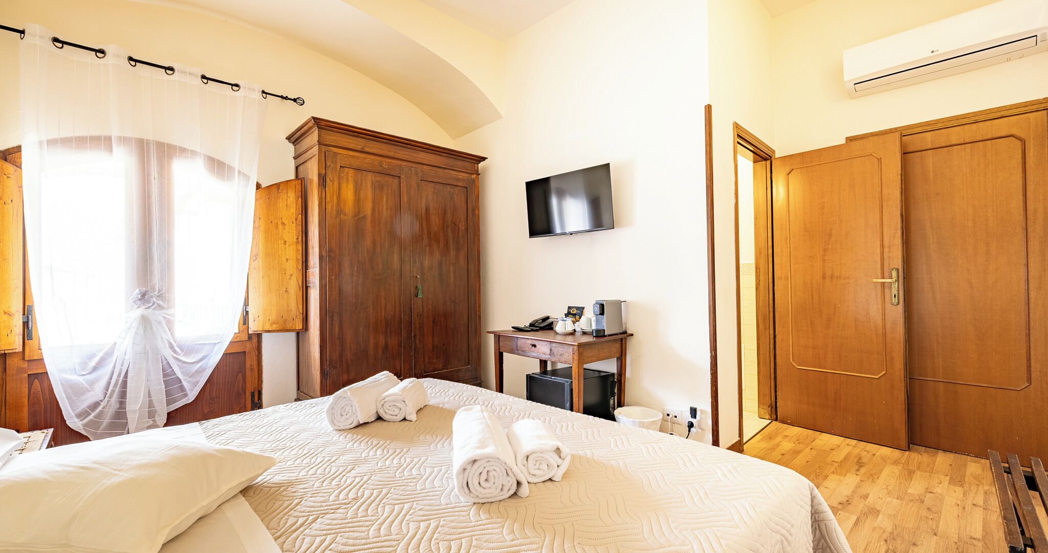 A hotel room with a bed, a desk, a TV, and a wardrobe.