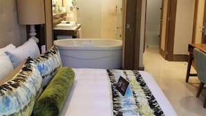 A hotel room with a large bed, a sitting area with a chair, a desk, a bathroom with a bathtub, and a shower. - Luxury Vidanta Resort Escape - Pools, Lazy River Beach Access, family-friendly (Q.R.)