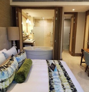 A hotel room with a large bed, a sitting area with a chair, a desk, a bathroom with a bathtub, and a shower. - Luxury Vidanta Resort Escape - Pools, Lazy River Beach Access, family-friendly (Q.R.)