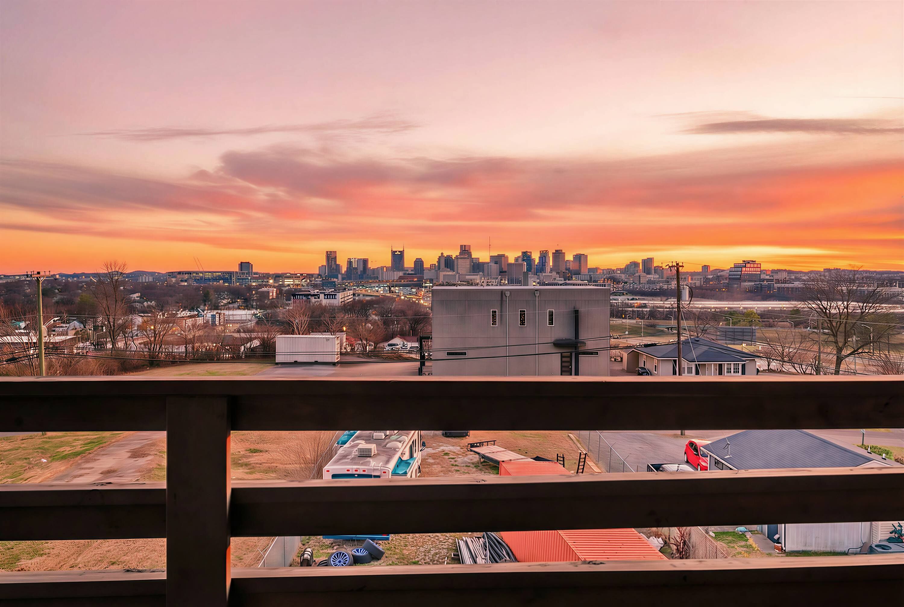 A city skyline at sunset with a view of a parking lot and a building in the foreground.