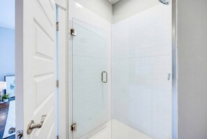 A modern bathroom with a glass shower enclosure, white tiled walls, and a visible shower control panel. - Summer pool, hot tub, game room, mini golf near Broadway & Nissan Stadium (Nashville)