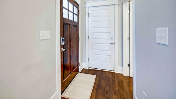 A hallway with a wooden door, a white door, and a light-colored rug on the floor. - Nashville sleeps 24: 2 homes, hot tub & game room near broadway (Nashville)