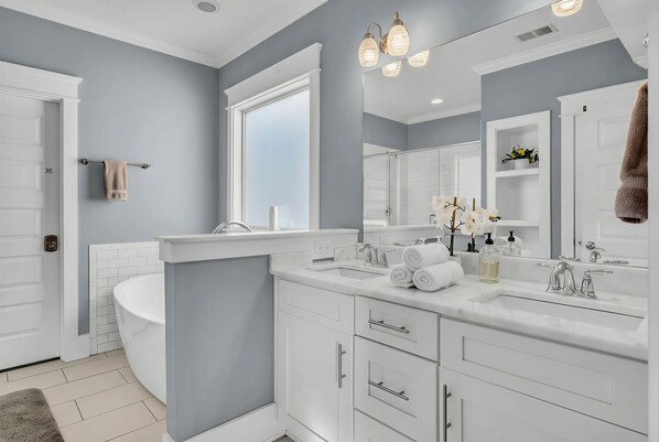 A modern bathroom with a freestanding bathtub, white cabinetry, and a large mirror. - Summer pool, hot tub, game room, mini golf near Broadway & Nissan Stadium (Nashville)