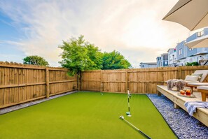 A backyard with a green lawn, wooden fence, and a pool table. - Summer pool, hot tub, game room, mini golf near Broadway & Nissan Stadium (Nashville)