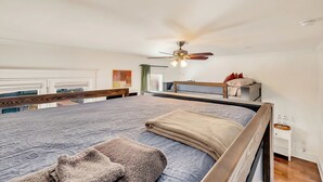 A modern bedroom with a large bed, a ceiling fan, and a view of the outside. - Nashville sleeps 24: 2 homes, hot tub & game room near broadway (Nashville)