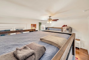 Ein modernes Schlafzimmer mit einem großen Bett, einem Deckenventilator und Blick ins Freie.