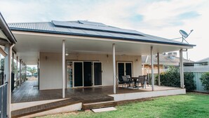 Un espacio exterior techado con patio, una mesa de comedor con sillas y una antena parabólica.