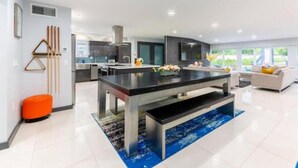 A modern kitchen with a central island, a dining area, and a sofa. - Athletic Villa Football Field Gym Cinema (North Miami)