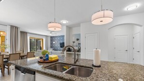 Een moderne keuken met granieten aanrecht, roestvrijstalen apparatuur en hanglampen.