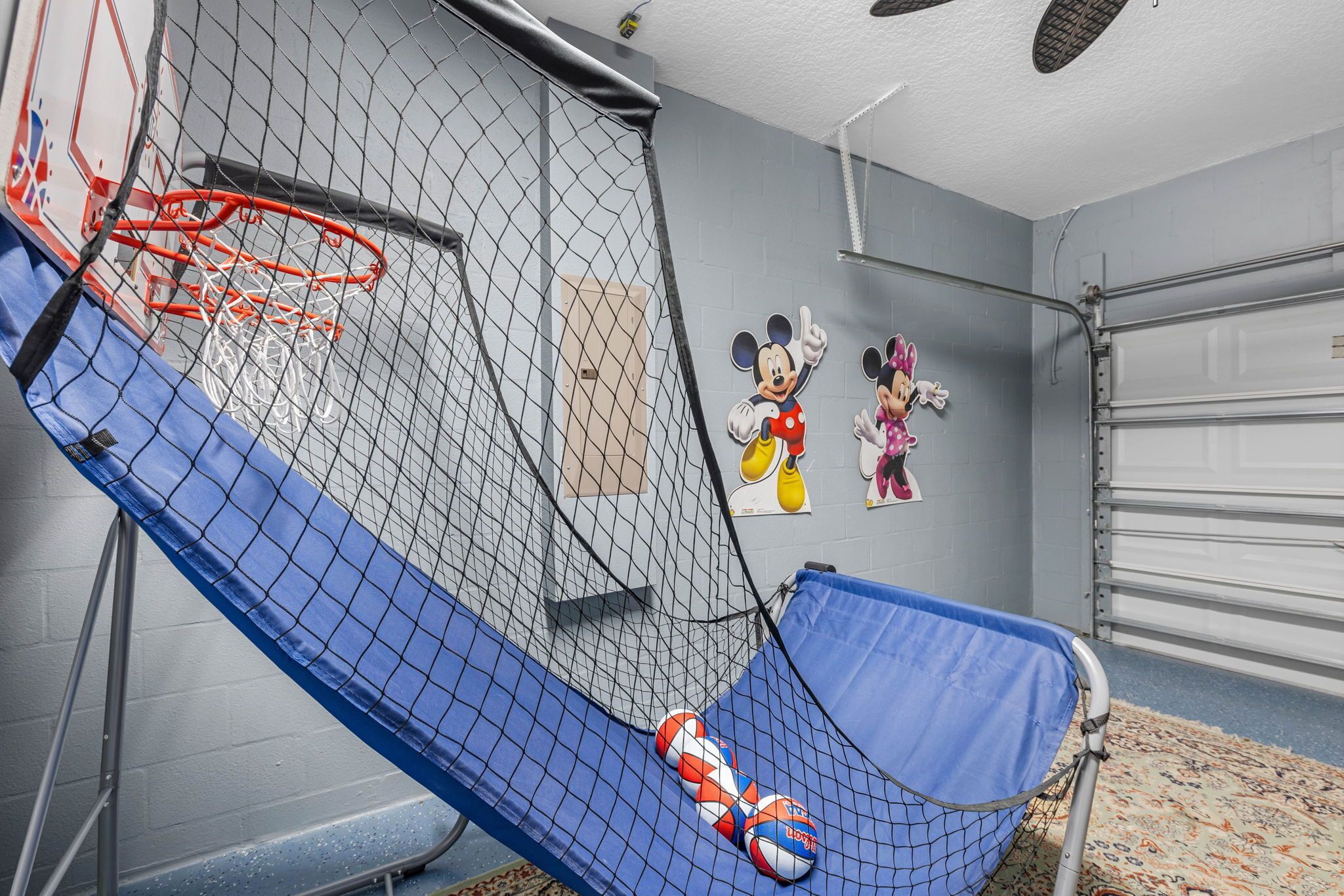 A basketball hoop with a blue net, a blue slide, and two basketballs.