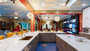 Un restaurant moderne doté d’un îlot central, d’un espace salon et d’un grand écran de télévision diffusant différentes chaînes.