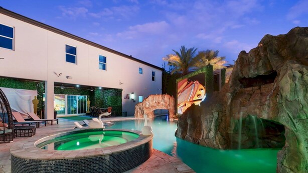 Un espace piscine extérieur moderne, doté d’un jacuzzi, d’une formation rocheuse et d’une fresque murale.