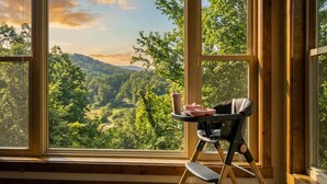 A room with a large window offering a view of a forested valley. - Designer Cabin | Mtn Views | Game Room | Hot Tub (Sevierville)