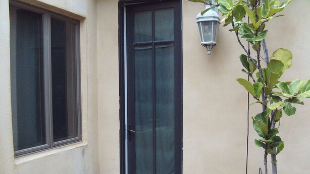 A door with a glass panel, a small outdoor area with a doormat, and a potted plant. - Peaceful studio with AC in charming Laguna Hills (Laguna Hills)