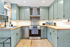 A compact kitchen with light green cabinets, a stainless steel range, and a dishwasher. - Peaceful Lakeside Cottage ~ Sunsets & Lake Access (Maitland)