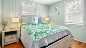 A bedroom with a bed, two bedside tables, a nightstand, and a window with blinds. - Last minute and Fall specials! Walk to beach! 4br 4ba Perfect location  (North Myrtle Beach)