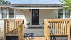 A single-story house with a front porch, a black front door, and two potted plants on either side. - Last minute and Fall specials! Walk to beach! 4br 4ba Perfect location  (North Myrtle Beach)