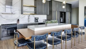 A modern kitchen with a central island, dark cabinetry, and a marble backsplash. - Club Wyndham Margaritaville Inspired 2 Bedroom Deluxe in Atlanta (Atlanta)