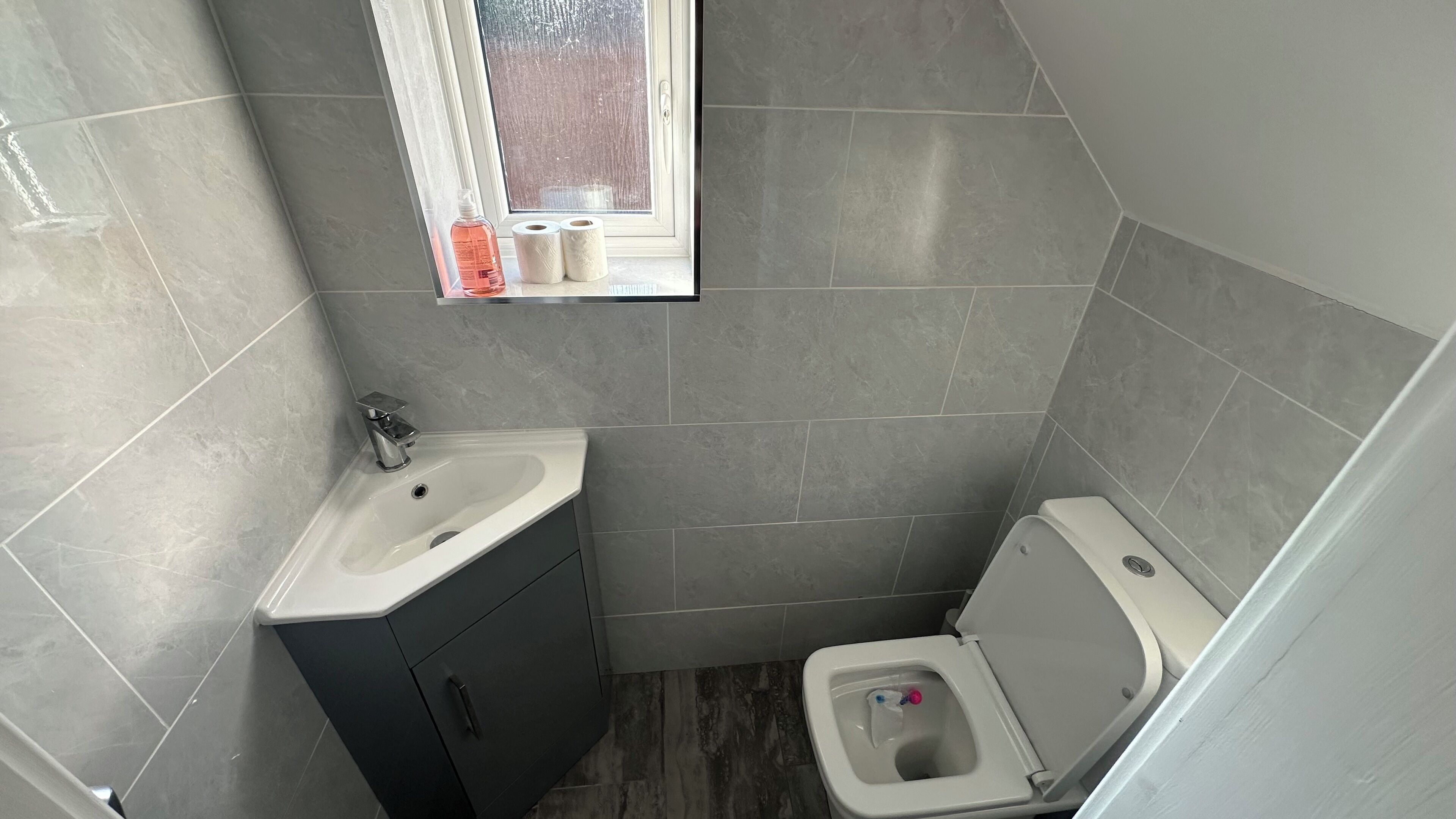 A compact bathroom with a sink, toilet, and window.